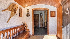 Un couloir avec un banc en bois, un panier tressé et une porte dotée d’une poignée en métal.