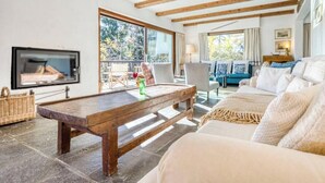 Un salon avec une table basse en bois, un canapé, un téléviseur et un balcon aménagé avec du mobilier d’extérieur.