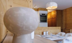 Eine moderne Küche mit Holzschränken, einem eingebauten Backofen und einer Pendelleuchte.