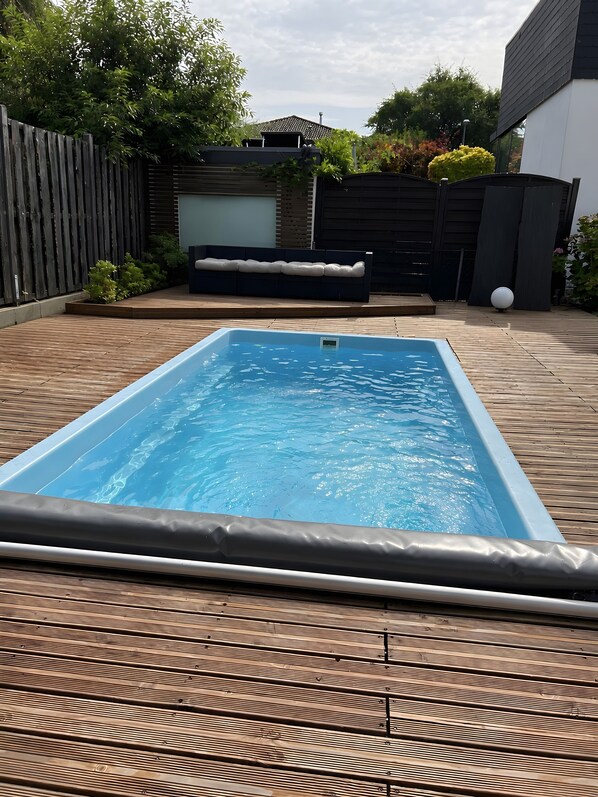 A rectangular swimming pool with a wooden deck surrounding it.
