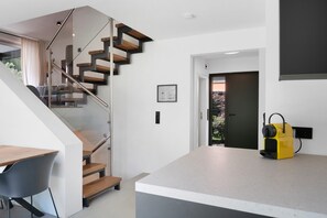 A modern interior with a staircase, a kitchen island, and a door leading outside.