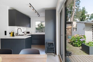 A modern kitchen with dark cabinetry, a white countertop, and a built-in oven.