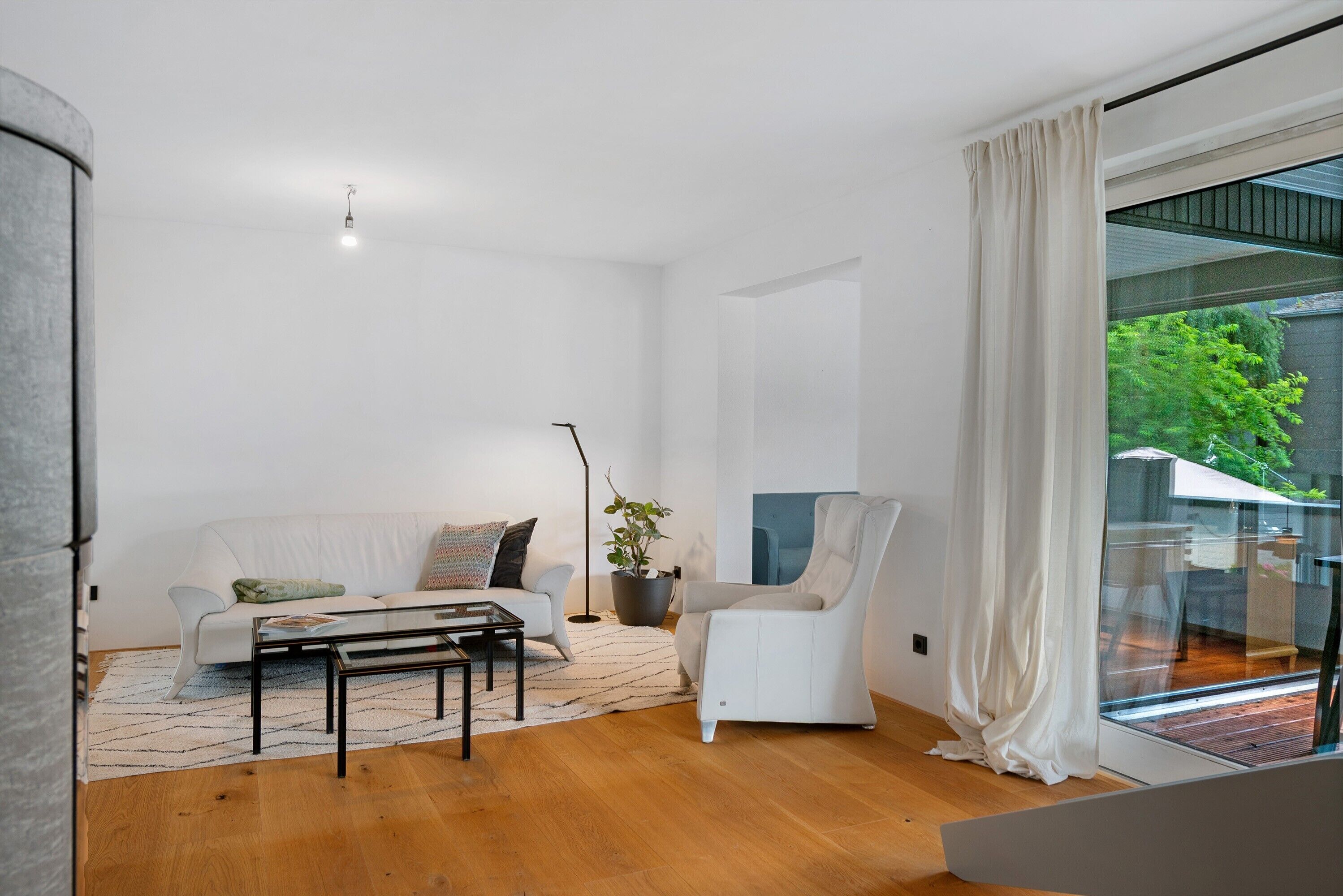 Ein modernes Wohnzimmer mit Sofa, Ohrensessel, Couchtisch und einer Topfpflanze.