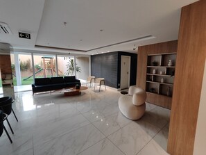 Ein modernes Wohnzimmer mit einer Couch, einem Couchtisch und Sesseln, einem Holzregal und Blick auf einen Spielplatz.