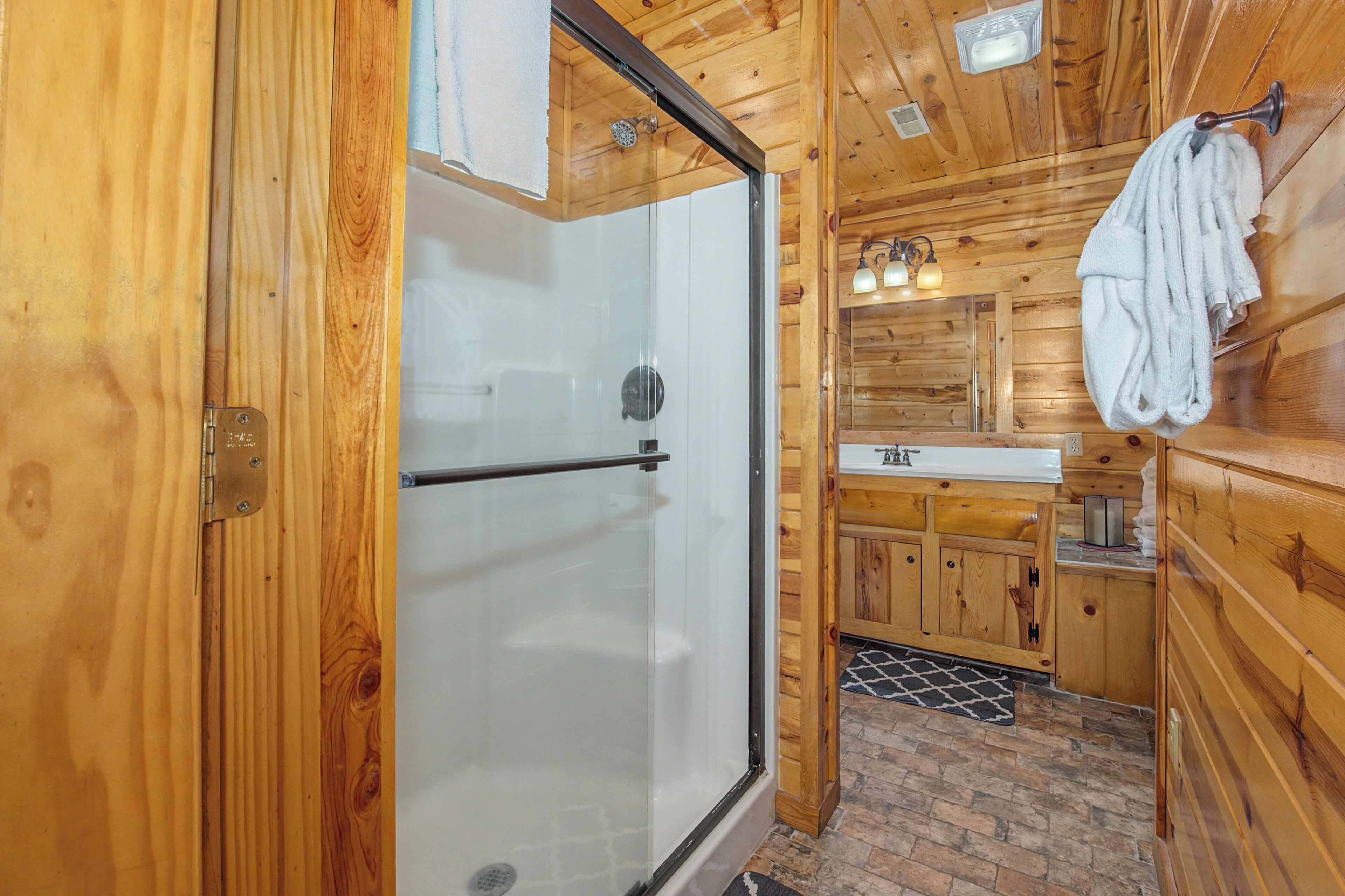 Een houten interieur met een douchecabine van glas, een wastafel en een handdoekhouder.