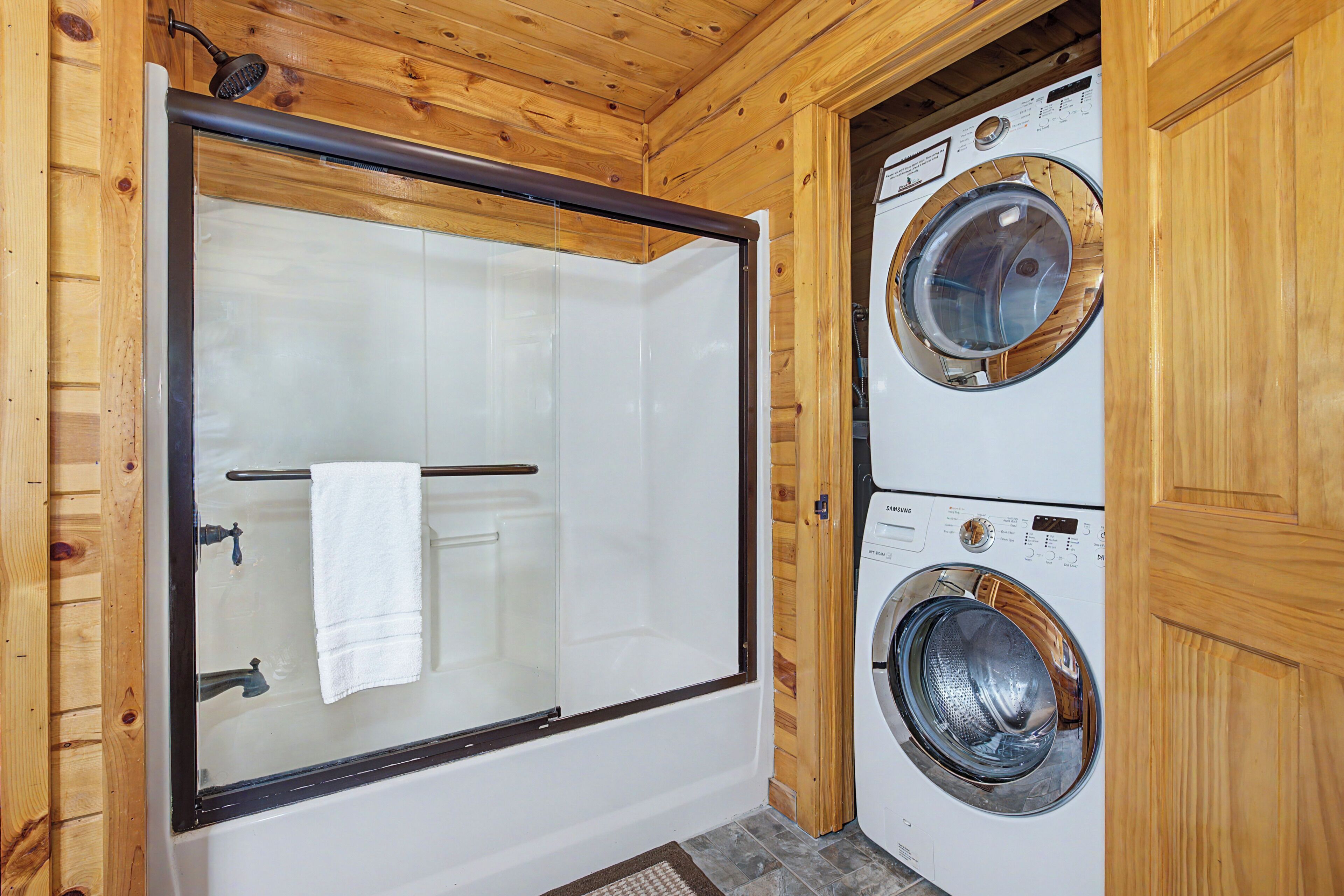 L’intérieur d’une cabane en bois, avec une douche en verre et un lave-linge à chargement frontal.
