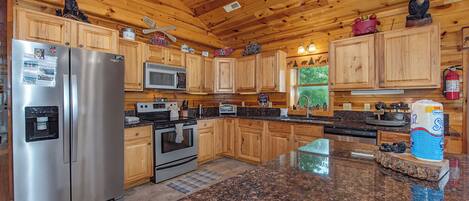 A kitchen with wooden cabinets, stainless steel appliances, granite countertops, and a central island.