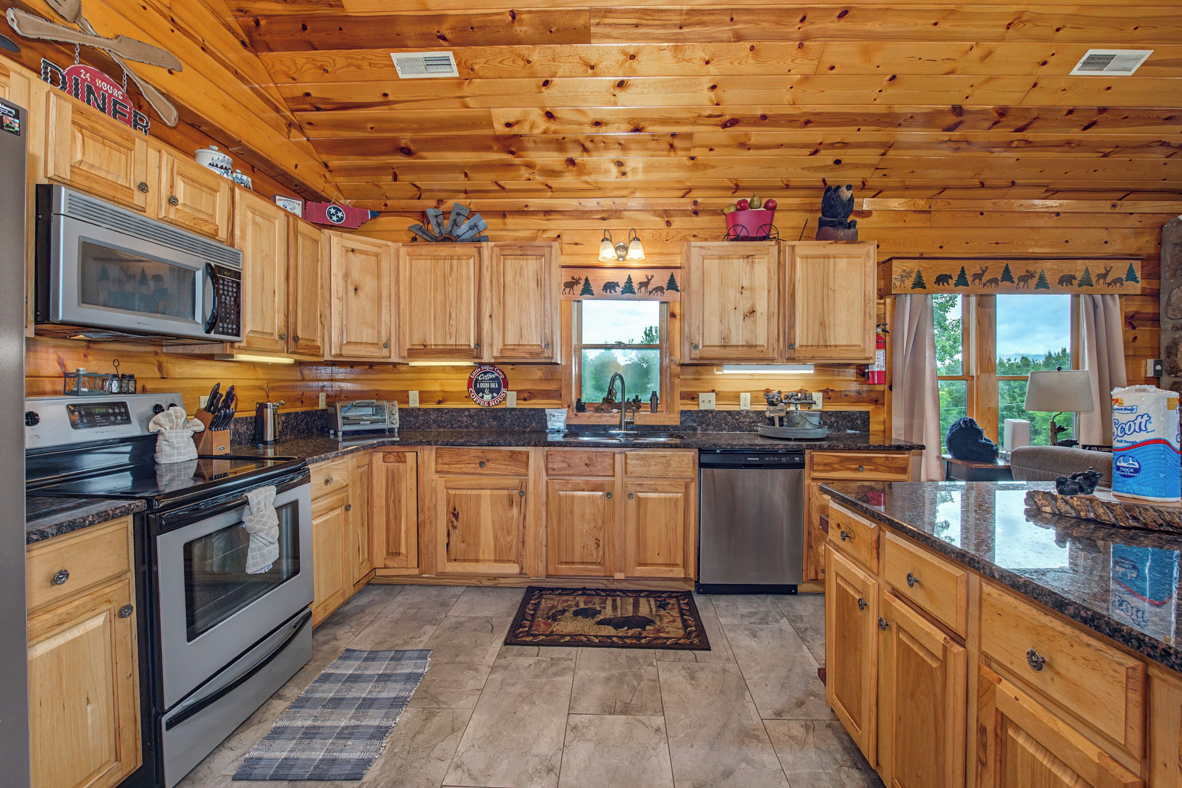 A wooden cabin interior with a kitchen featuring wooden cabinets, a microwave, stove, and a dishwasher.