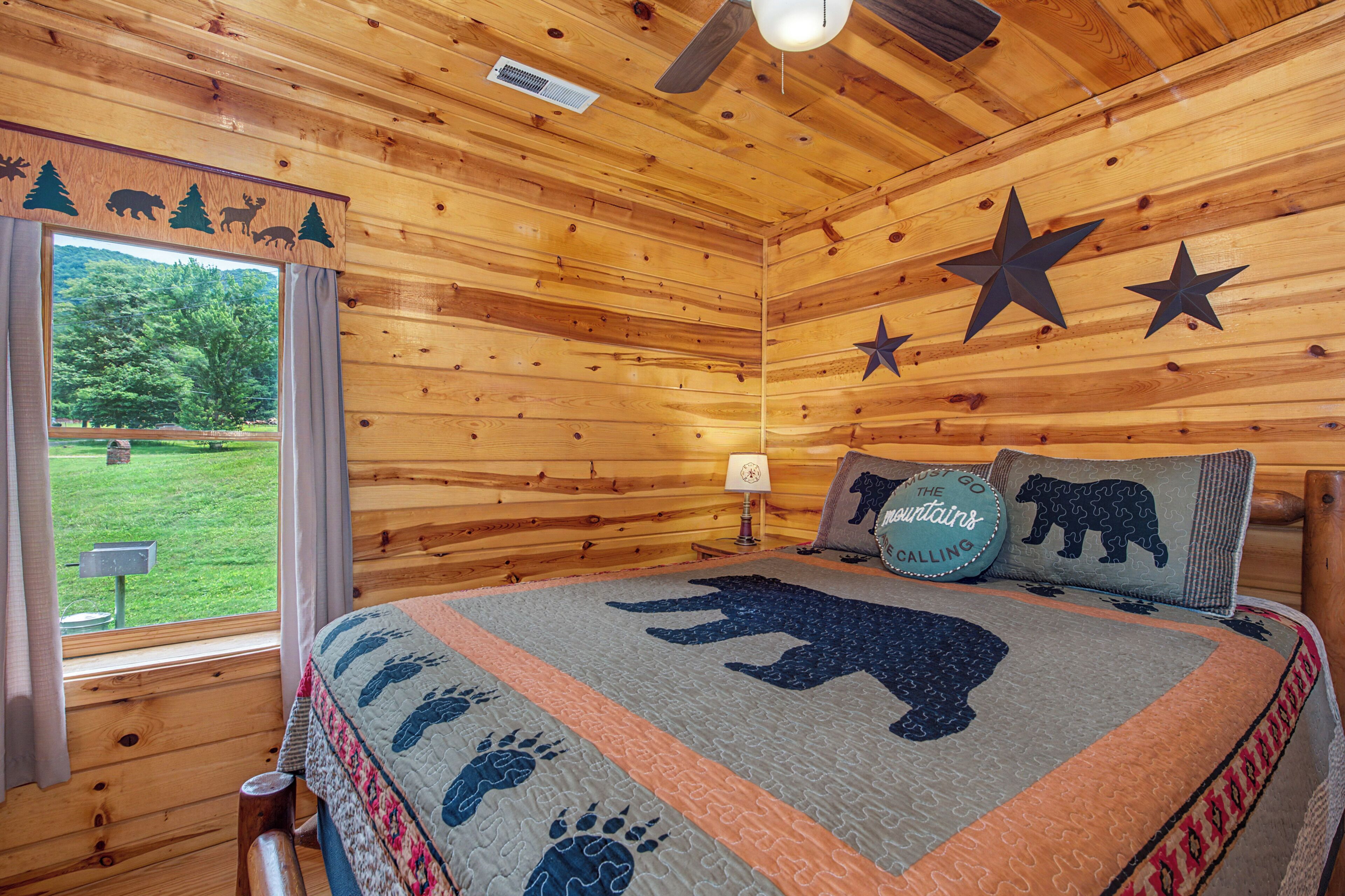 A log cabin bedroom with a bed, star decorations, a window with curtains, and a view of the outdoors.