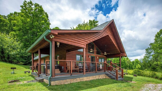 Eine Holzhütte mit Veranda, Sitzgelegenheiten im Freien und einem Steinfundament.