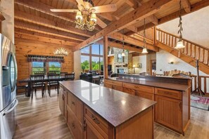 A spacious kitchen with a large island, wooden cabinets, and a stone fireplace. - Escape to Heaven's Hidden View, a spectacular 6-bedroom, 5-bathroom mountain ret (Sevierville)
