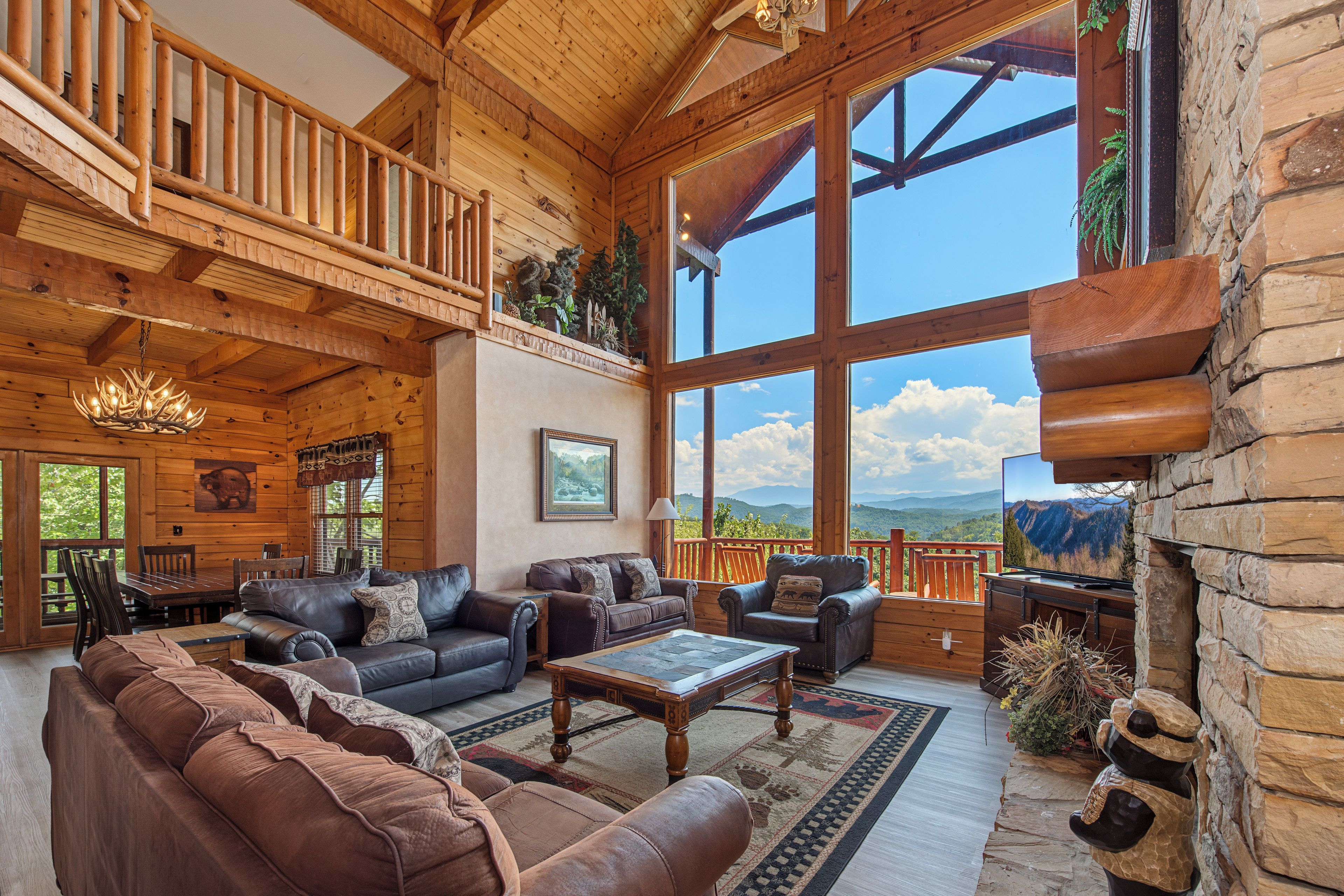 Un intérieur spacieux en bois, doté d’une grande fenêtre offrant une vue sur les montagnes, d’une cheminée et d’un coin salon confortable.