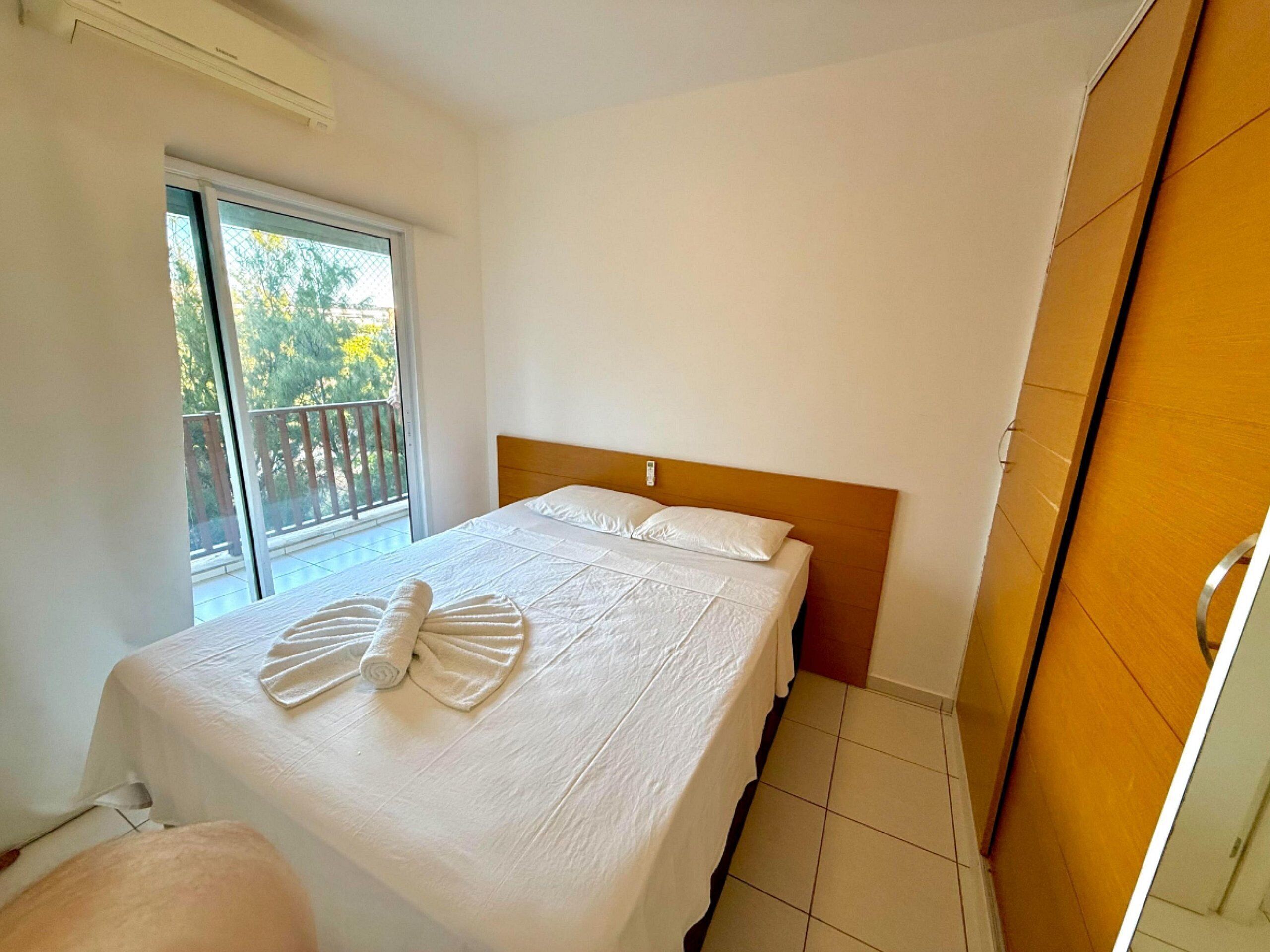 Quarto de hotel com cama, janela e varanda.