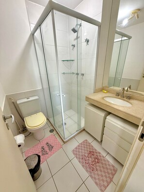 Ein Badezimmer mit Duschkabine, Toilette, Waschbecken und Spiegel.