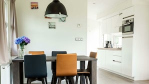 Una cocina moderna con armarios blancos, horno integrado y cafetera.