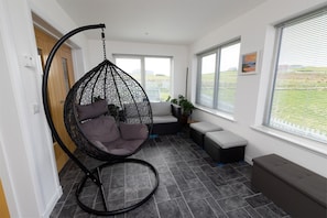 A room with a hanging chair, a bench, and a potted plant.