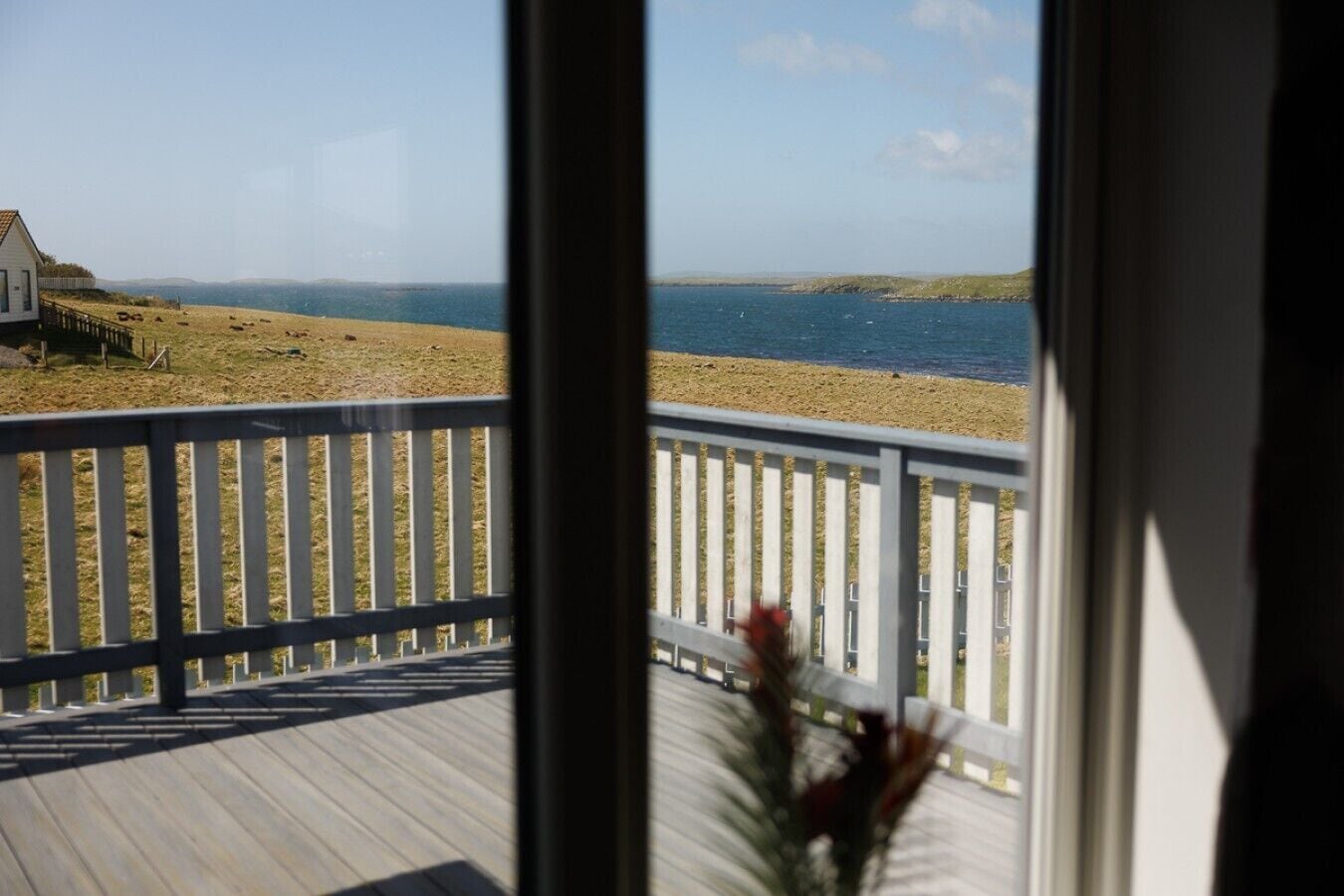 Une vue depuis un balcon donnant sur une plage, avec une terrasse en bois et une balustrade blanche.