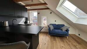A modern loft apartment with a kitchen, a dining area, a blue sofa, and a skylight. - Stylish BERNHARD Apartment in STRAND HAUS 10 (Borkum)