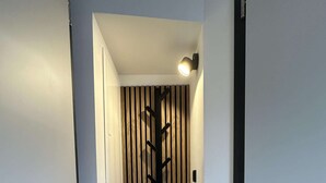 A hallway with a wooden floor, a wall-mounted light fixture, and a door with a vertical striped pattern. - Stylish BERNHARD Apartment in STRAND HAUS 10 (Borkum)