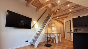 Eine moderne Küche mit Einbauherd, ein Essbereich mit Tisch und Stühlen sowie eine Treppe zu einer oberen Ebene.