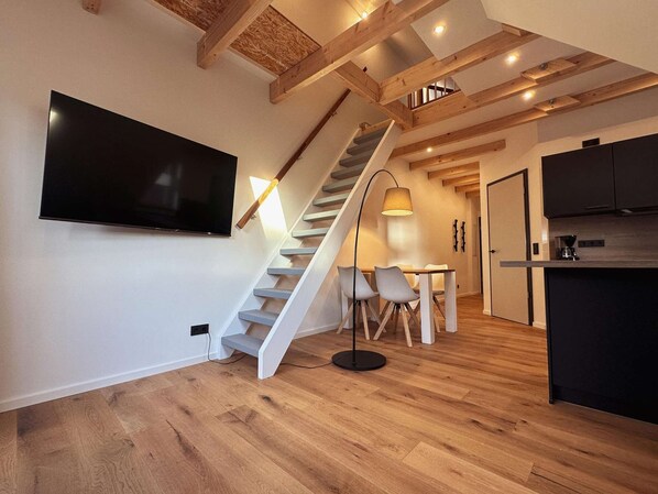 Une cuisine moderne dotée d’une cuisinière intégrée, un coin repas avec une table et des chaises, et un escalier menant à un niveau supérieur.