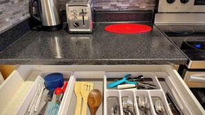 A kitchen with a toaster, kettle, and red baking mat on the countertop.