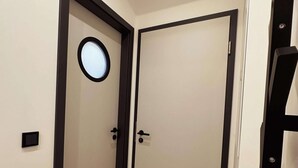 A hallway with two doors, one with a circular window, and a wooden floor. - Stylish OSTEREMS Apartment in STRAND HAUS 10 (Borkum)