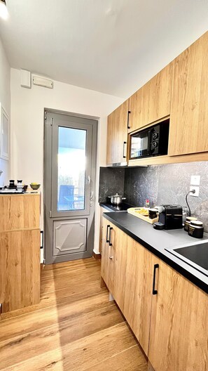 Una cocina moderna con armarios de madera, encimera negra y microondas.