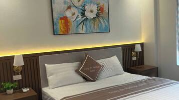 Une chambre d’hôtel avec un grand lit, une table de chevet avec une lampe, un tableau accroché au mur et une petite table de chevet ornée d’une plante.