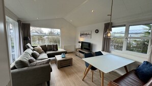 A spacious living area with a sofa, a dining table, and a TV. - Holiday Home in Noordwijk With Terrace (Noordwijk)