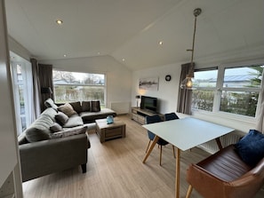 A spacious living area with a sofa, a dining table, and a TV. - Holiday Home in Noordwijk With Terrace (Noordwijk)