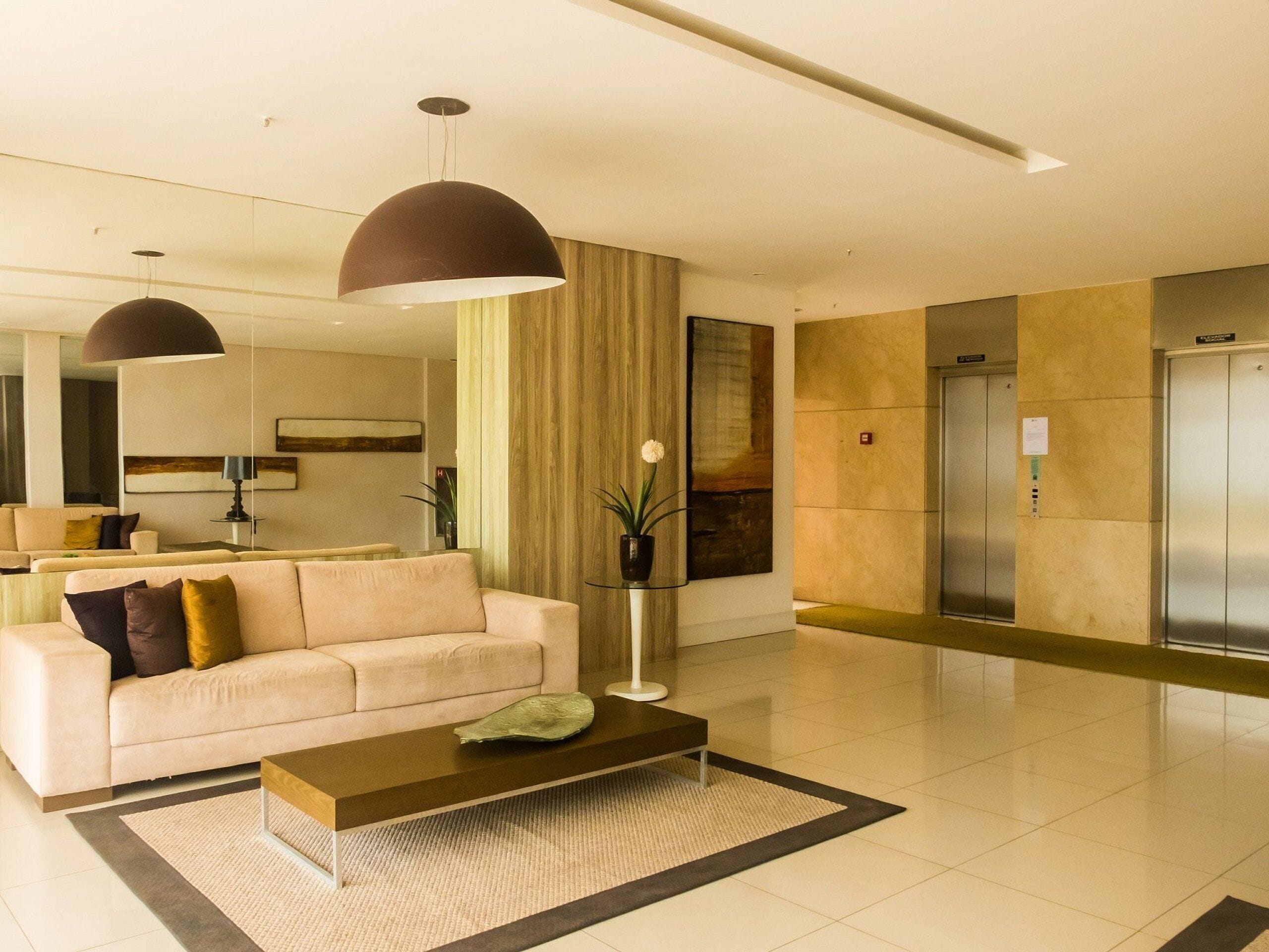 Um hall moderno com um sofá, mesa de centro e um espelho grande.
