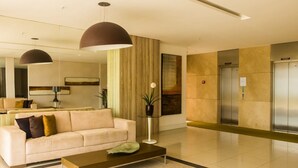 A modern lobby with a sofa, coffee table, and a large mirror. - Beach Village sea View 2 Bedrooms (Fortaleza)