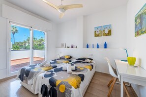 A bedroom with a bed, a desk, a chair, and a balcony with a view. - Arkadia – Beachfront Penthouse with Private Pool (Mijas Costa)