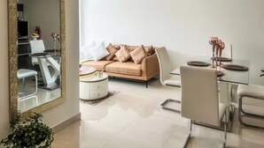 A modern living room with a beige sofa, a glass dining table, and a large mirror with a gold frame. - Blaze 1 (Quito)