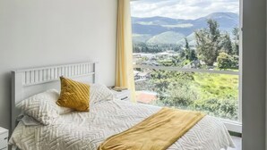 Un dormitorio con cama, mesita de noche y ventana con vistas al paisaje.