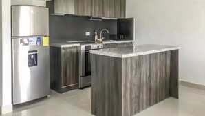Una cocina moderna con una isla integrada, electrodomésticos de acero inoxidable y armarios de madera oscura.