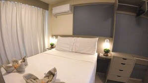 Une chambre d’hôtel comprenant un lit, des tables de chevet, un appareil de climatisation, un bureau et une chaise.