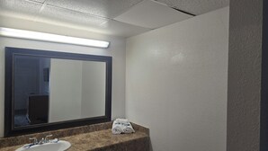 A bathroom with a sink, mirror, towel rack, and ceiling lights. - Cajun Inn  (Shreveport)