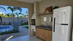 Eine Küche mit Kühlschrank, Spüle und Arbeitsplatte. Durch die Glastür ist ein Pool zu sehen.
