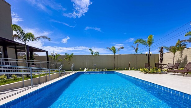 Ein Swimmingpool mit klarem, blauem Wasser, umgeben von einer überdachten Sitzgelegenheit mit Stühlen und einer Pergola.