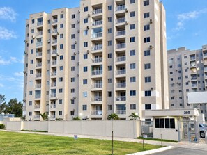 A multi-story residential building with balconies, a gated entrance, and a clear sky. - Apartamento Novinho 2 Quartos e Vista mar (Fortaleza)