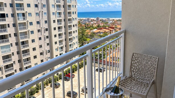 A balcony with two chairs, a table, and a bottle of champagne. - Apartamento Novo 2 Quartos e Vista mar 1001b (Fortaleza)