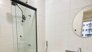 A bathroom with a glass-enclosed shower, a toilet, and a sink with a mirror above it. - Apartamento Novo 2 Quartos e Vista mar 1001b (Fortaleza)