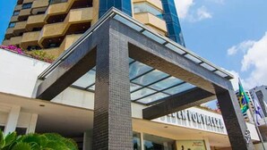 A tall building with a modern design, featuring a glass facade and a prominent entrance with a metal canopy. - Golden Flat By Fortaleza Temporada (Fortaleza)