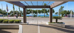 A covered pedestrian area with a view of the sea, a kiosk, and flags. - Golden Flat By Fortaleza Temporada (Fortaleza)