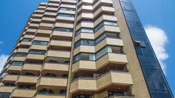 Un edificio de gran altura con piscina en la base, que cuenta con varios balcones y un diseño arquitectónico moderno.