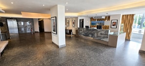 A spacious lobby with a reception desk, framed artwork, and a modern kitchen area with stainless steel appliances.