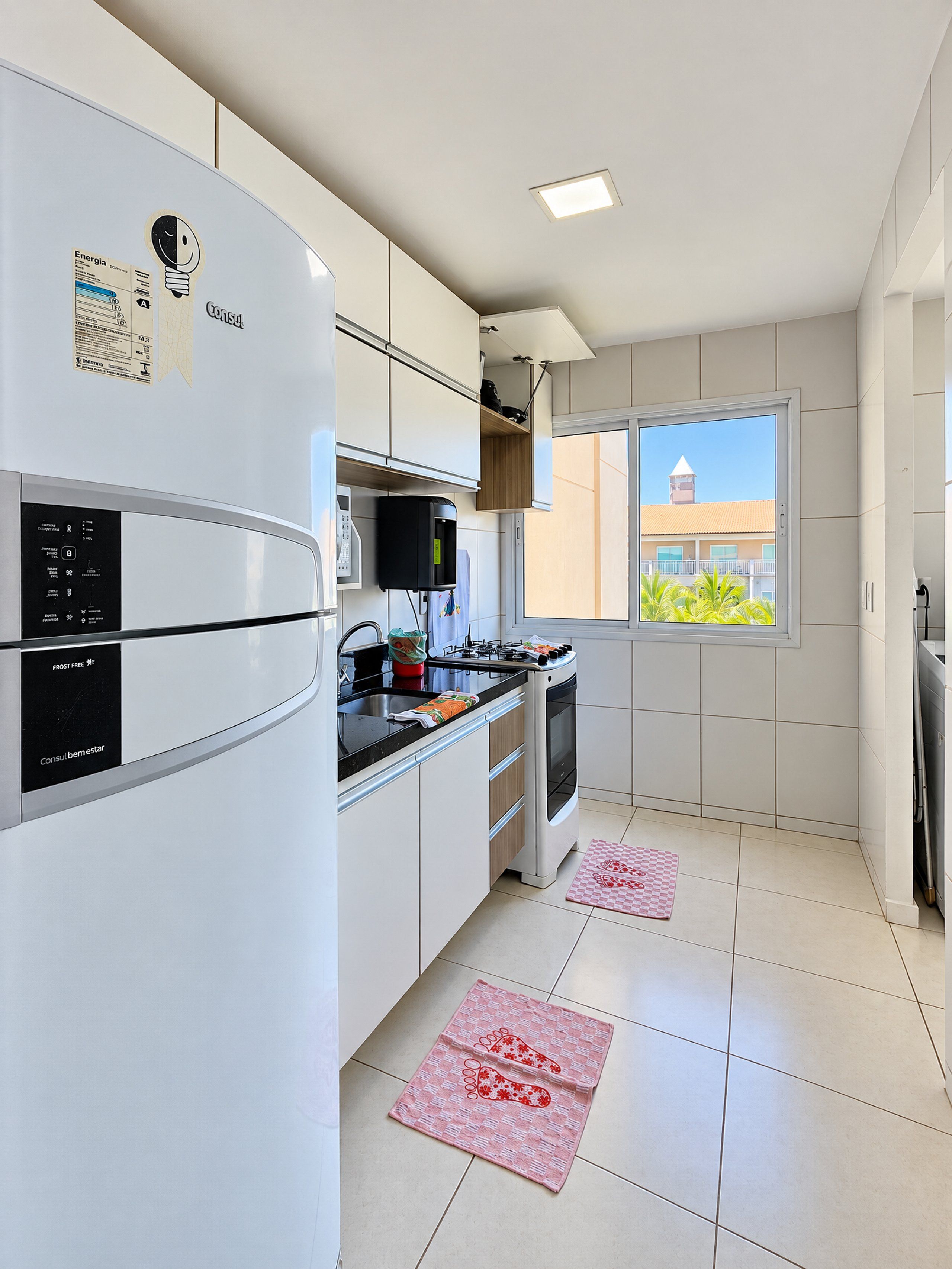 A modern kitchen with white cabinetry, a built-in oven, and a window overlooking a building.