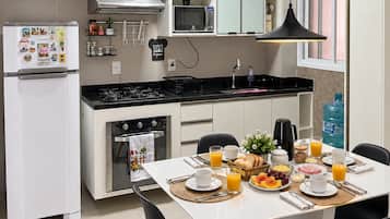 A modern kitchen with white cabinets, a microwave, a stove, and a dining area with a table set for breakfast.